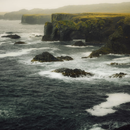 Stormy day, rainy and moody, at Arnastapi in Iceland with a lonely man on the cliffs, in front of Atlantic Oceanの写真素材