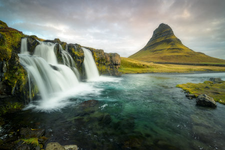 Kirkjufellfoss waterfall in Iceland with the iconic Kirkjufell mountain, dramatic skyの写真素材
