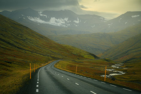 Empty road in northern Iceland, going through a valley surrounded by mountains, moody weatherの写真素材