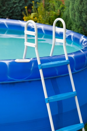Detail of a blue portable swimming pool with a small ladder and water in itの写真素材