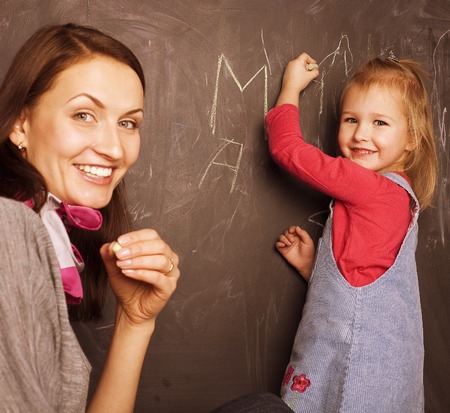 young pretty teacher with pupil in classroomの写真素材