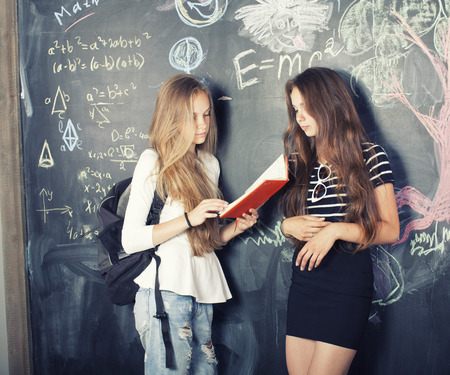 back to school after summer vacations, two teen girls in classroom with blackboard paintedの写真素材