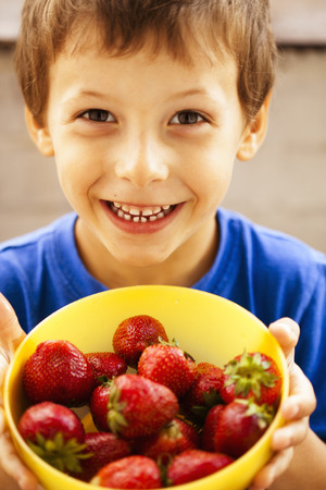 little cute boy eating strawberry close up, concept adorableの写真素材