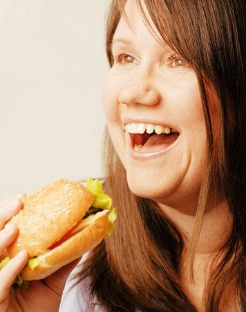 fat white woman having choice between hamburger and salad isolatedの写真素材