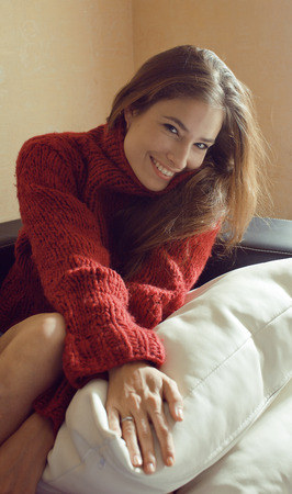 young pretty real woman in sweater and scarf all over her face smilingの写真素材