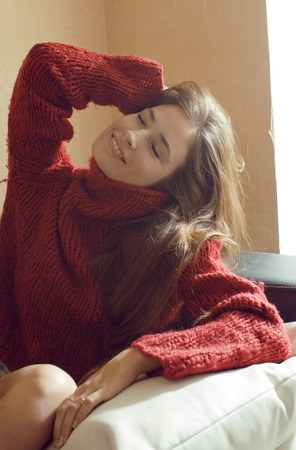 young pretty real woman in sweater and scarf all over her face smilingの写真素材
