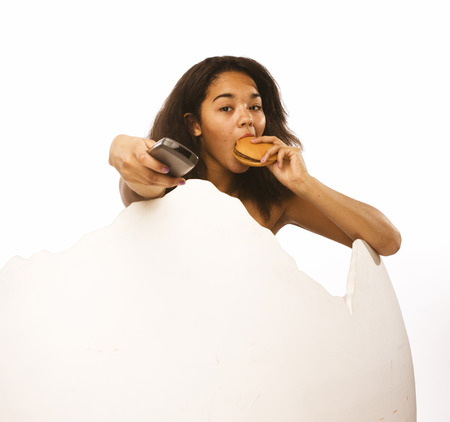 young fat african american teen girl with remote and hamburger isolated, unhealthy obsessedの写真素材