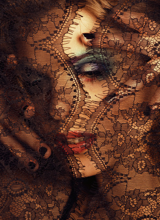 portrait of beauty young woman through lace close upの写真素材