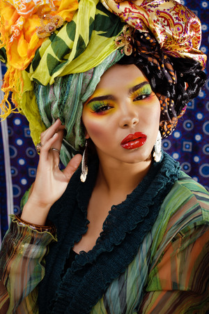 beauty bright woman with creative make up, many shawls on head like cubian woman, ethno lookの写真素材