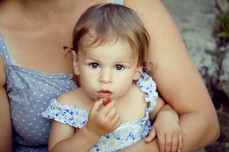 little girl with mother outside with berry close upの写真素材