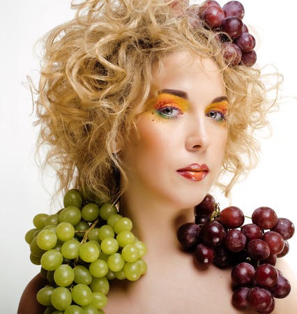 cute blond woman with creative make up and grapes isolated, funny crazy beautyの写真素材