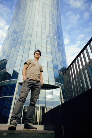 young man stand in front of modern business building perspectiveの写真素材