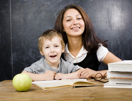 little cute boy with teacher in classroom at desk close upの写真素材