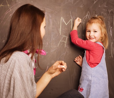 teacher with pupil in classroom at blackboard writtingの写真素材