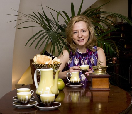 mature blonde woman with curly hairstyle drinking tea at luxury homeの写真素材