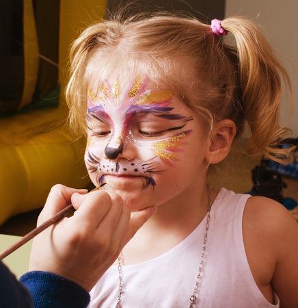 little girl with faceart on birthday party in processの写真素材