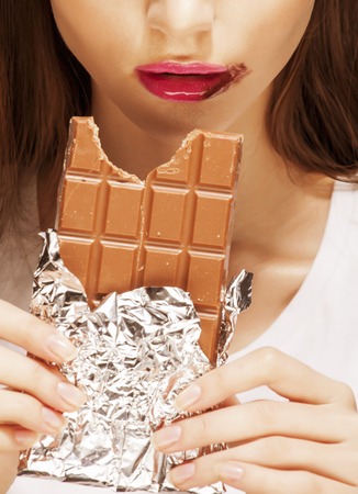 close up portrait  brunette girl with bar of chocolate, dirty mouth on whiteの写真素材