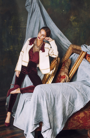 beauty rich brunette woman in luxury interior near empty frames, vintage elegance, goldの写真素材