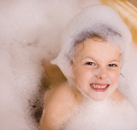 cute little boy in bathroom with foam making facesの写真素材