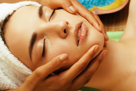 stock photo attractive lady getting spa treatment in salon, close up asian tan hands on faceの写真素材