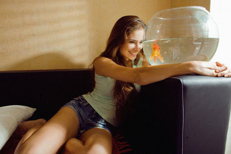 pretty woman playing with goldfish at home, sunlight morning smilingの写真素材