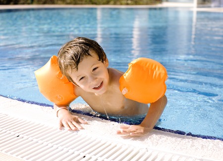 little cute boy in swimming pool wearing orange handcarvesの写真素材