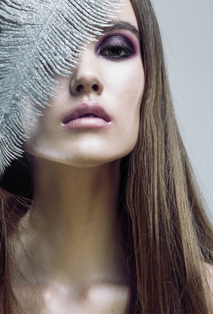 young pretty woman with silver feather like ice decoration to new year, face close upの写真素材