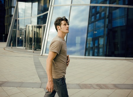 young man stand in front of modern business building, dreams come trueの写真素材