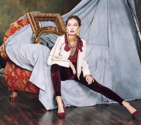 beauty rich brunette woman in luxury interior near empty frames, vintage elegance, gold close upの写真素材