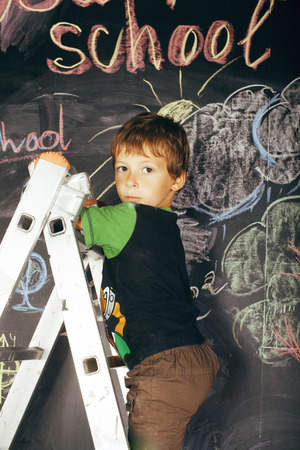 little cute real boy at blackboard in classroom, back to schoolの写真素材