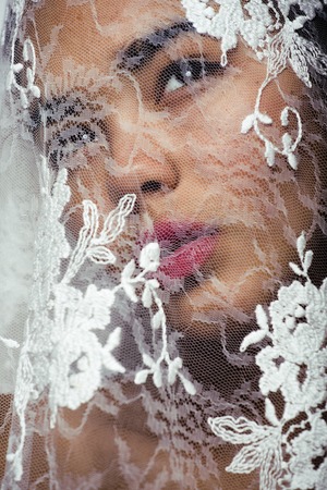 portrait of beauty young afro woman through white lace, like new bride under veil close upの写真素材