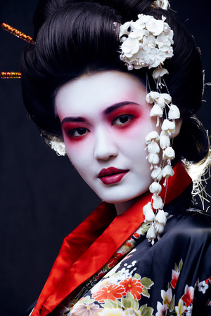 young pretty geisha in kimono with sakura and decoration on black backgroundの写真素材