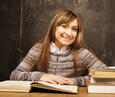 portrait of happy cute brunette emothional student in classroom at blackboard close upの写真素材