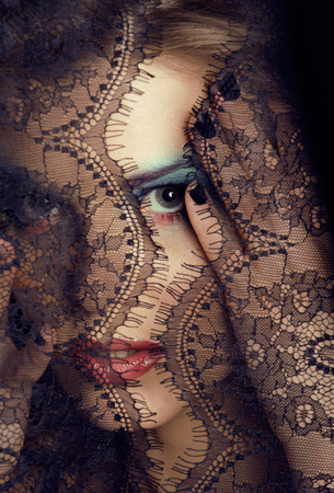 portrait of beauty young woman through lace close upの写真素材