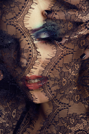 portrait of beauty young woman through lace close upの写真素材