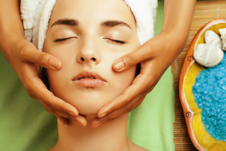 stock photo attractive lady getting spa treatment in salon, close up asian tan hands on faceの写真素材