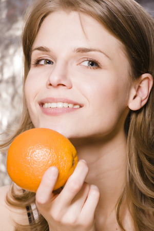 young pretty woman with orange close up smilingの写真素材