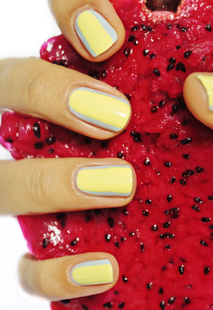 creative design manicure on fingernails, hand holding dragon fruit close up isolatedの写真素材