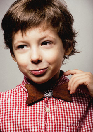 little cute boy in bowtie smiling, making funny faces close up, stylish casual outfitの写真素材
