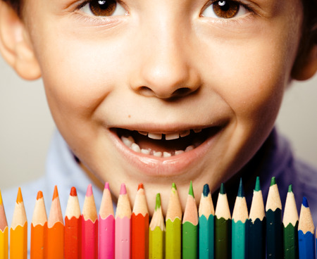 little cute boy with color pencils close up smiling, education face coloredの写真素材
