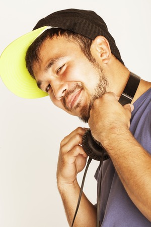 young asian man in hat and headphones listening music on white background close upの写真素材