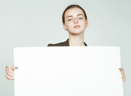 young pretty brunette girl with placard on white background wearing business costumeの写真素材
