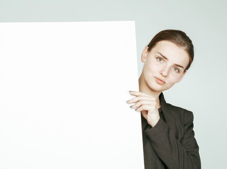 young pretty brunette girl with placard on white background wearing business costumeの写真素材