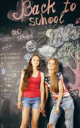 back to school after summer vacations, two teen real girls in classroom with blackboard painted together smilingの写真素材