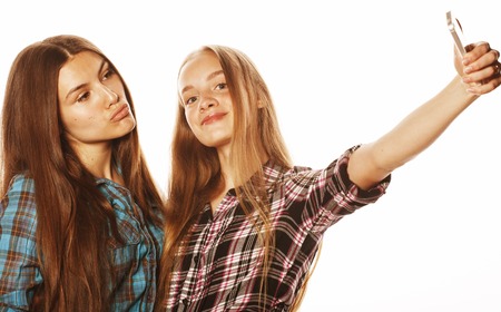 cute teenage girls making selfie isolated on whiteの写真素材