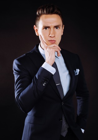 young pretty business man standing on black background, modern hairstyleの写真素材