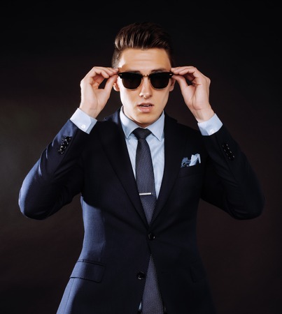 young pretty business man standing on black background, modern hairstyleの写真素材
