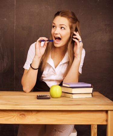 young pretty girl student in classroom at blackboard doing homeworkの写真素材