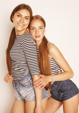 two cute teenagers having fun together isolated on white, girls friendsの写真素材
