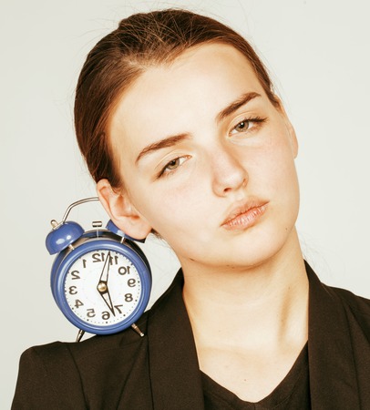 young beauty woman in business style costume waking up for work early morning on white background with clockの写真素材